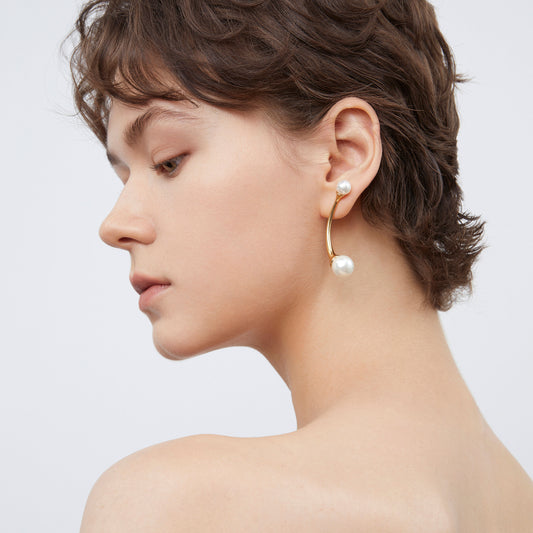 Close-up side view of gold C-shape pearl earrings by TIKOO highlighting the 18K gold plating.