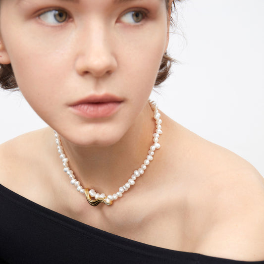 Close-up shot of the TIKOO organic wave gold pendant and natural pearls on a model, highlighting the premium craftsmanship.