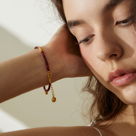 Lifestyle view of model wearing TIKOO natural garnet bracelet, highlighting the adjustable extension chain and gold shell charm.