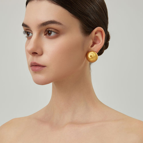 Close-up of TIKOO handcrafted original design brushed gold earrings showing texture.
