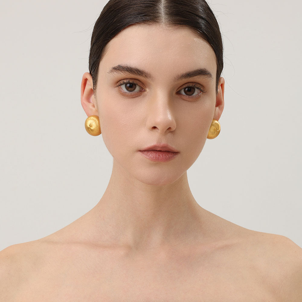 Close-up of TIKOO handcrafted original design brushed gold earrings showing texture.