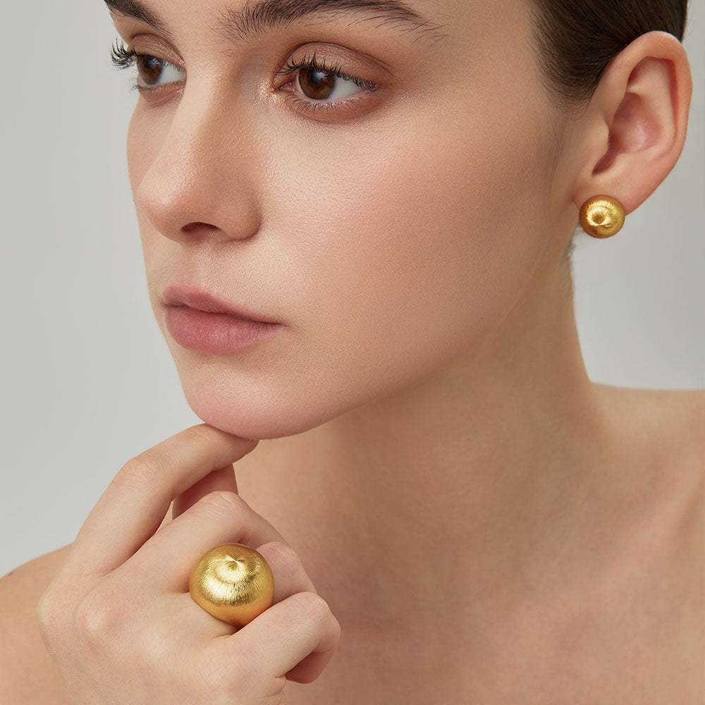Close-up of TIKOO handcrafted original design brushed gold earrings showing texture