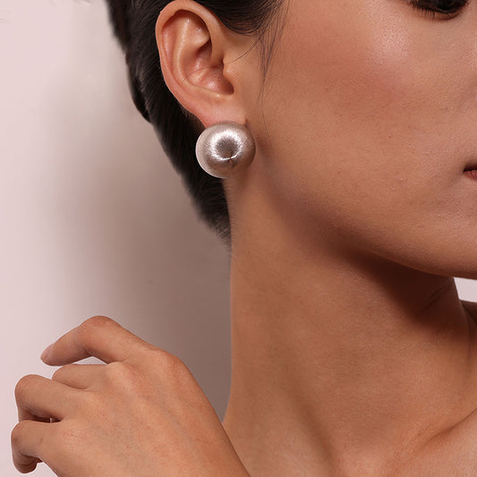 Close-up of TIKOO handcrafted brushed metal disc earrings on ear