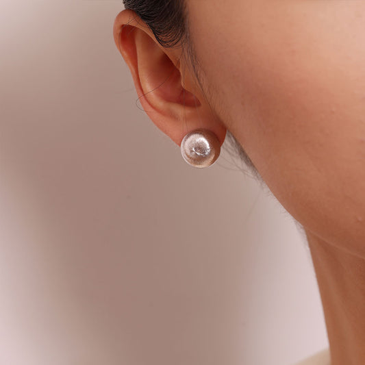 Close-up of TIKOO handcrafted brushed metal disc earrings on ear