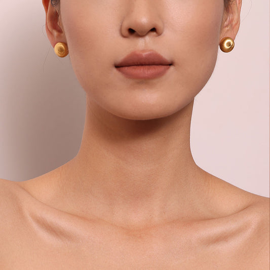 Close-up of TIKOO handcrafted original design brushed gold earrings showing texture