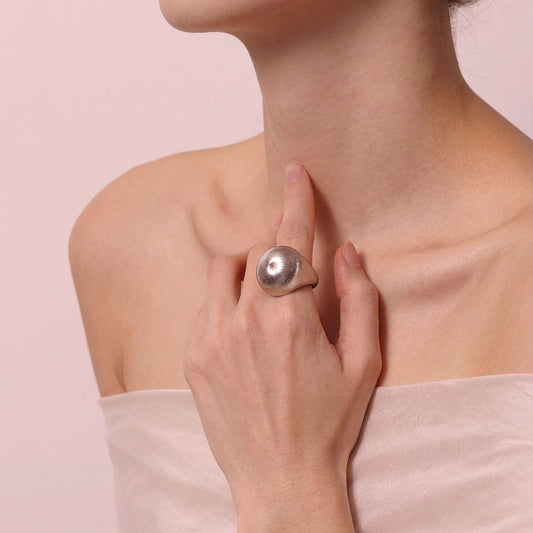 Close-up on a model's hand wearing the TIKOO thick white gold plated statement ring with brushed texture.