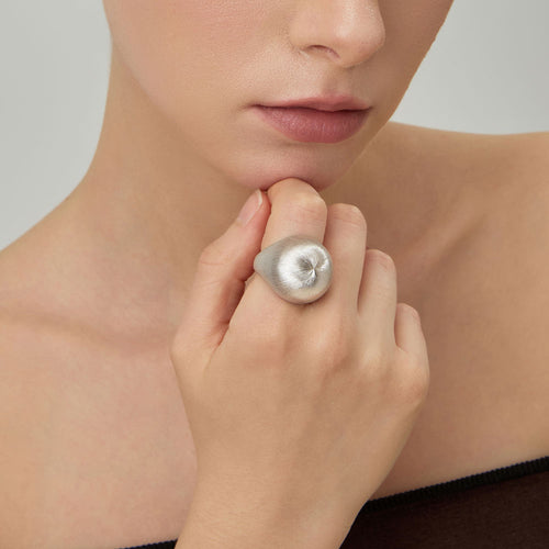 Close-up on a model's hand wearing the TIKOO thick white gold plated statement ring with brushed texture.