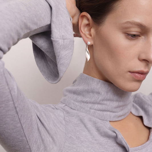 Fashion model styling the elegant TIKOO platinum plated pearl drop earrings for a modern look.