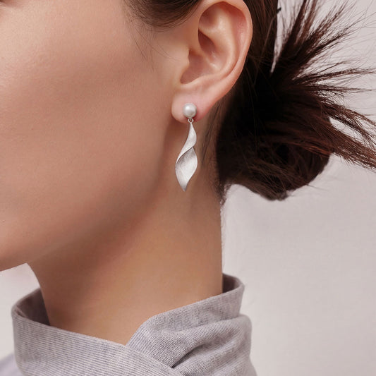 Side view of model wearing TIKOO modern silver-tone leaf and pearl drop earrings.