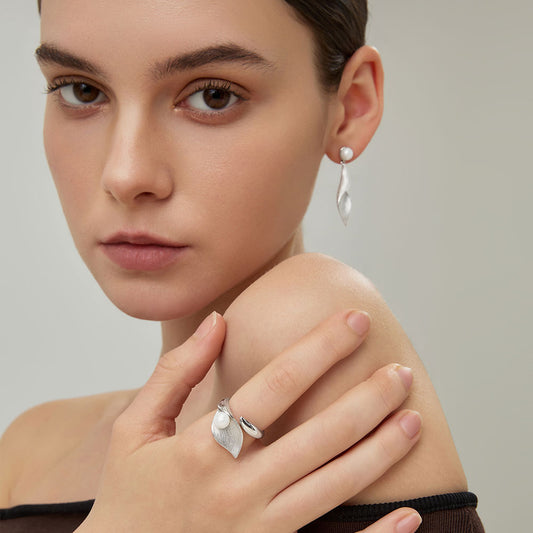 Close-up profile of the sculptural silver-plated twisted leaf dangle earrings on model.