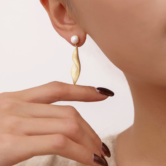 Close-up of the textured matte gold leaf earrings on model showcasing the twisted sculptural design.