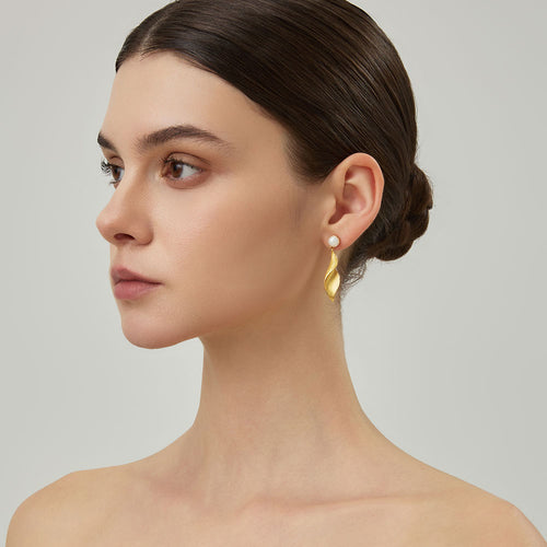 Close-up of the textured matte gold leaf earrings on model showcasing the twisted sculptural design.