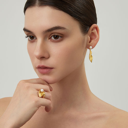 Close-up of the textured matte gold leaf earrings on model showcasing the twisted sculptural design.