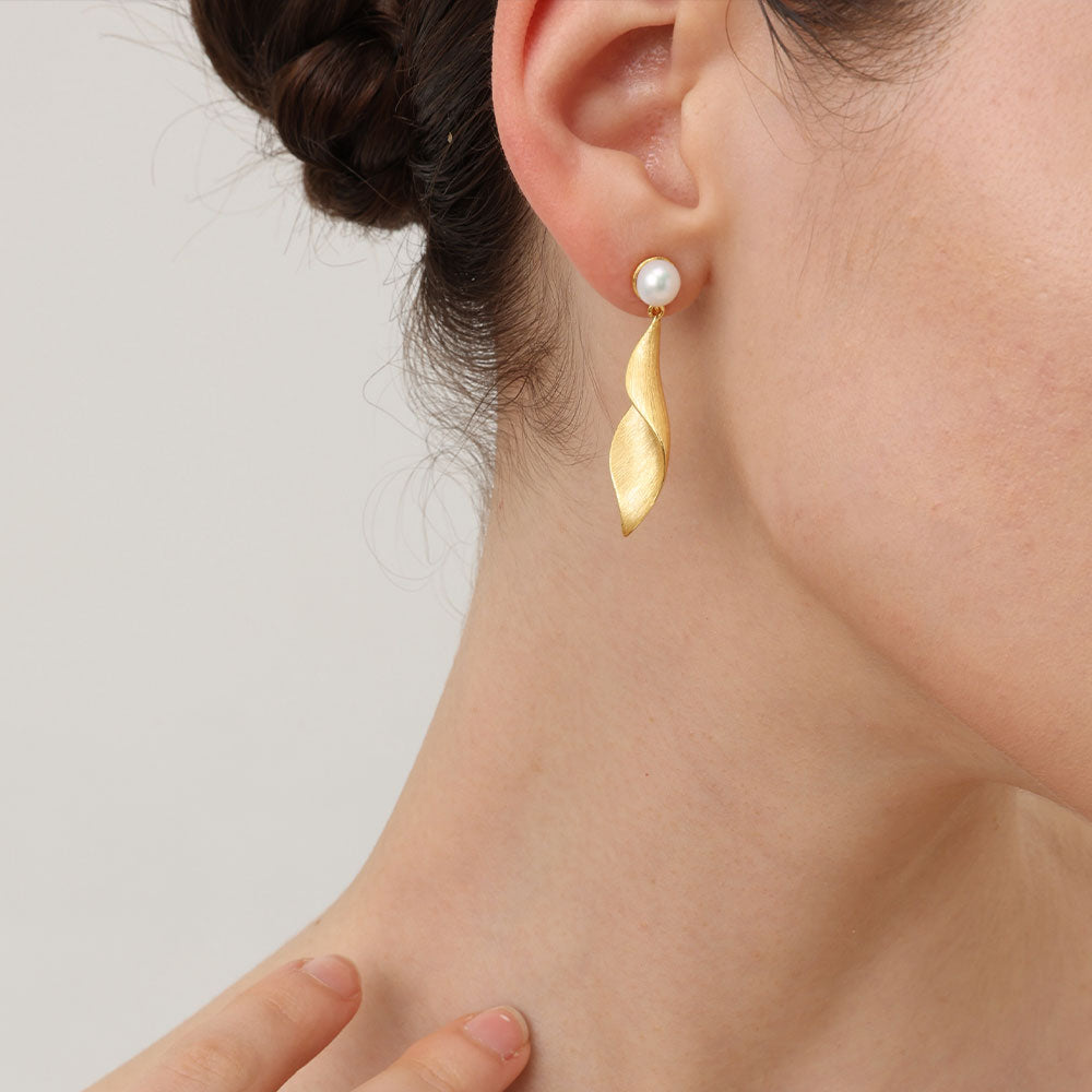 Close-up of the textured matte gold leaf earrings on model showcasing the twisted sculptural design.