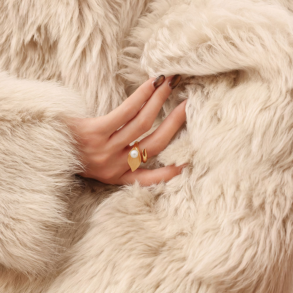 Close-up of a model wearing the TIKOO gold leaf and pearl statement ring with luxury winter fashion.