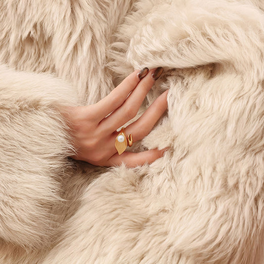 Close-up of a model wearing the TIKOO gold leaf and pearl statement ring with luxury winter fashion.