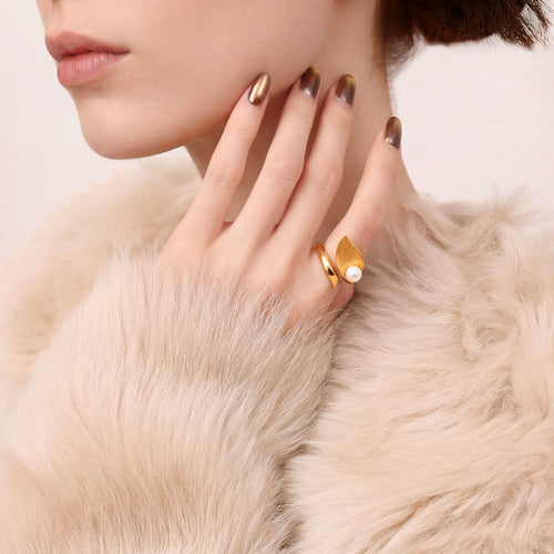 Close-up of a model wearing the TIKOO gold leaf and pearl statement ring with luxury winter fashion.