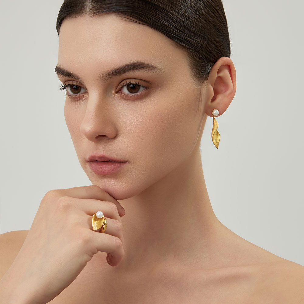 Close-up of a model wearing the TIKOO gold leaf and pearl statement ring with luxury winter fashion.