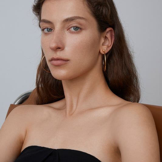 A model wearing TIKOO large gold-plated silver hoop earrings showing the perfect scale for minimalist styling.