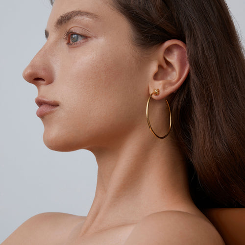 Side profile of a model wearing 925 sterling silver oversized hoops with a luxurious 18K gold finish.