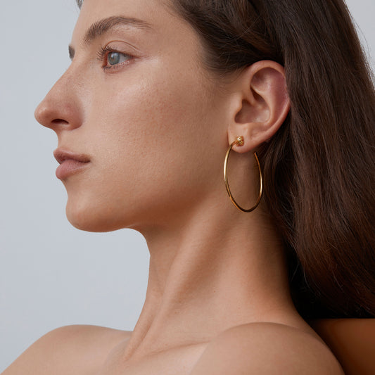 Side profile of a model wearing 925 sterling silver oversized hoops with a luxurious 18K gold finish.