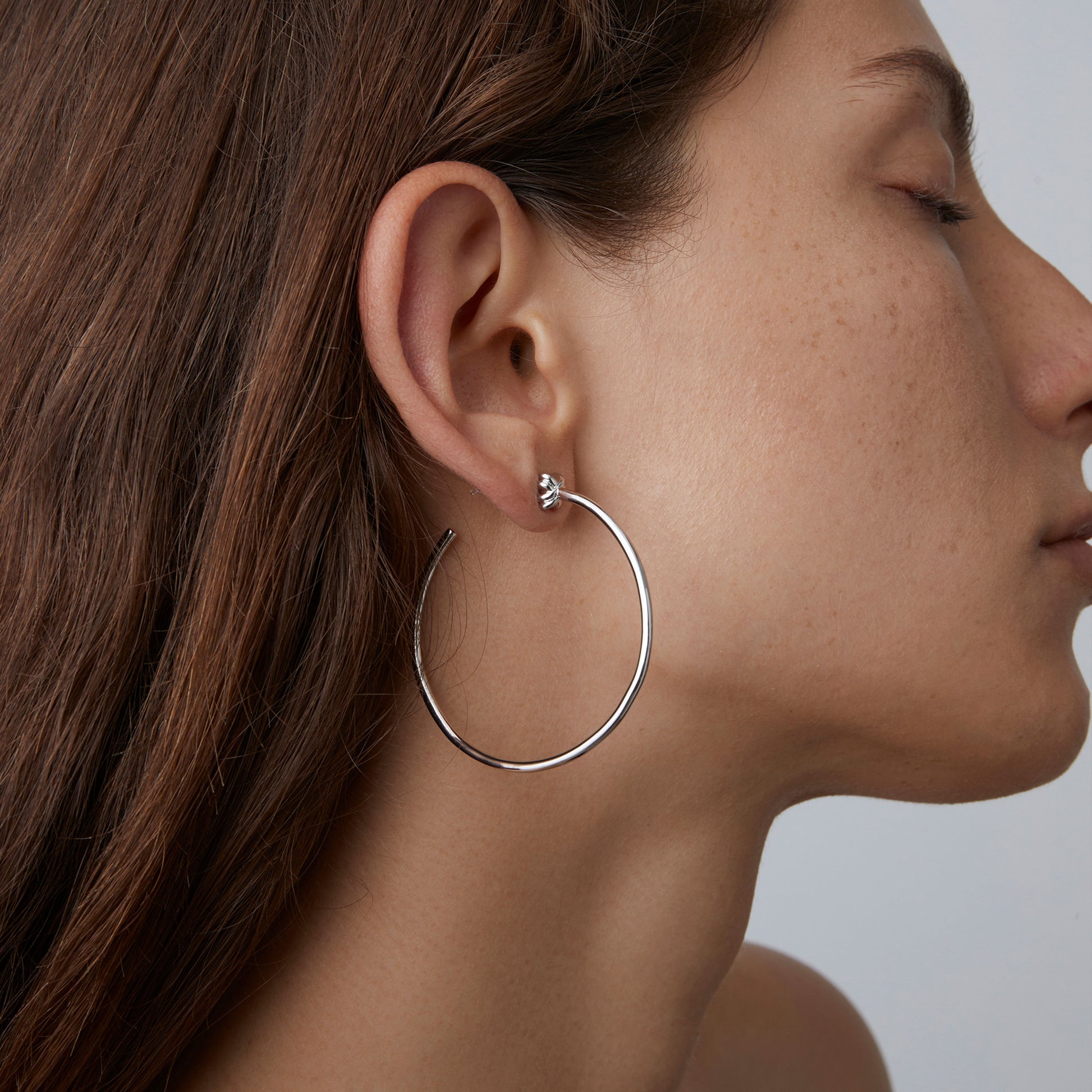 Model wearing TIKOO minimalist large silver hoop earrings showing the side profile and size.
