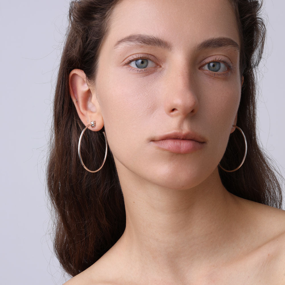 Front view of a model wearing high-shine white gold plated silver circle hoops by TIKOO.