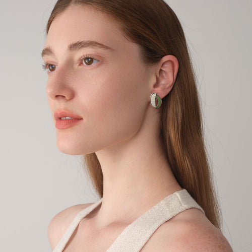 Close-up of TIKOO leaf-shaped leather studs on model, highlighting the textured top-grain leather and thick white gold plating.