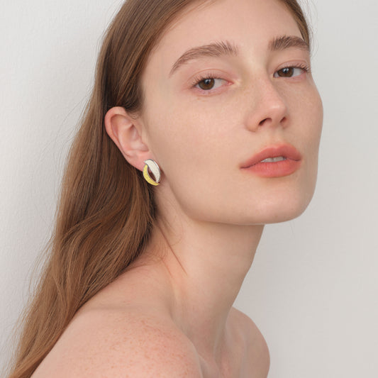 Fashion model wearing TIKOO white and yellow leather inlay earrings, showcasing a modern artistic jewelry look.
