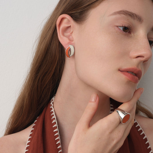 Close-up of TIKOO orange curved leather studs on model, styled with a matching orange leather ring for a coordinated look.