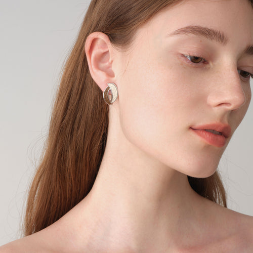 Fashion model wearing TIKOO brown and white leather inlay earrings, showcasing a modern professional jewelry look.