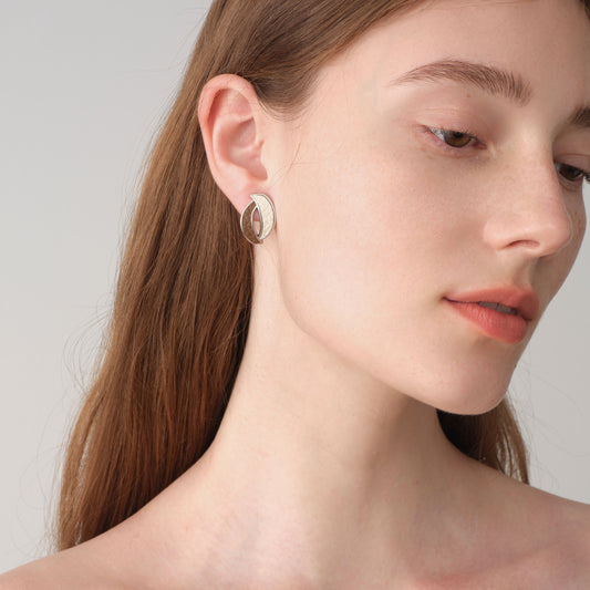 Fashion model wearing TIKOO brown and white leather inlay earrings, showcasing a modern professional jewelry look.