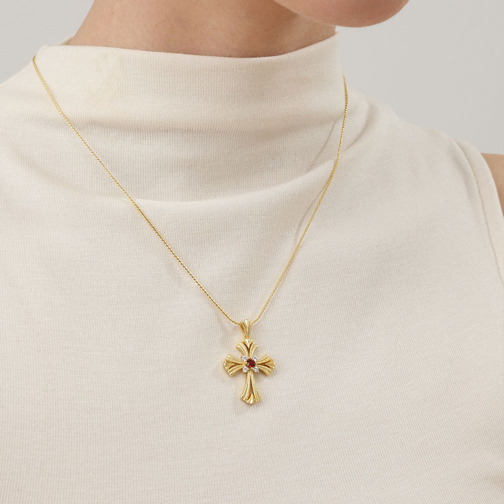 Model wearing a TIKOO original design red garnet and 18K gold plated cross necklace with a beige mock neck top.