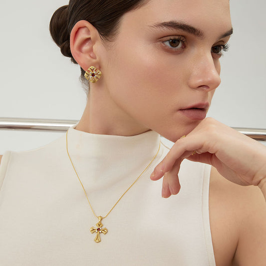 Profile view of model wearing TIKOO garnent cross necklace and matching gold studs.