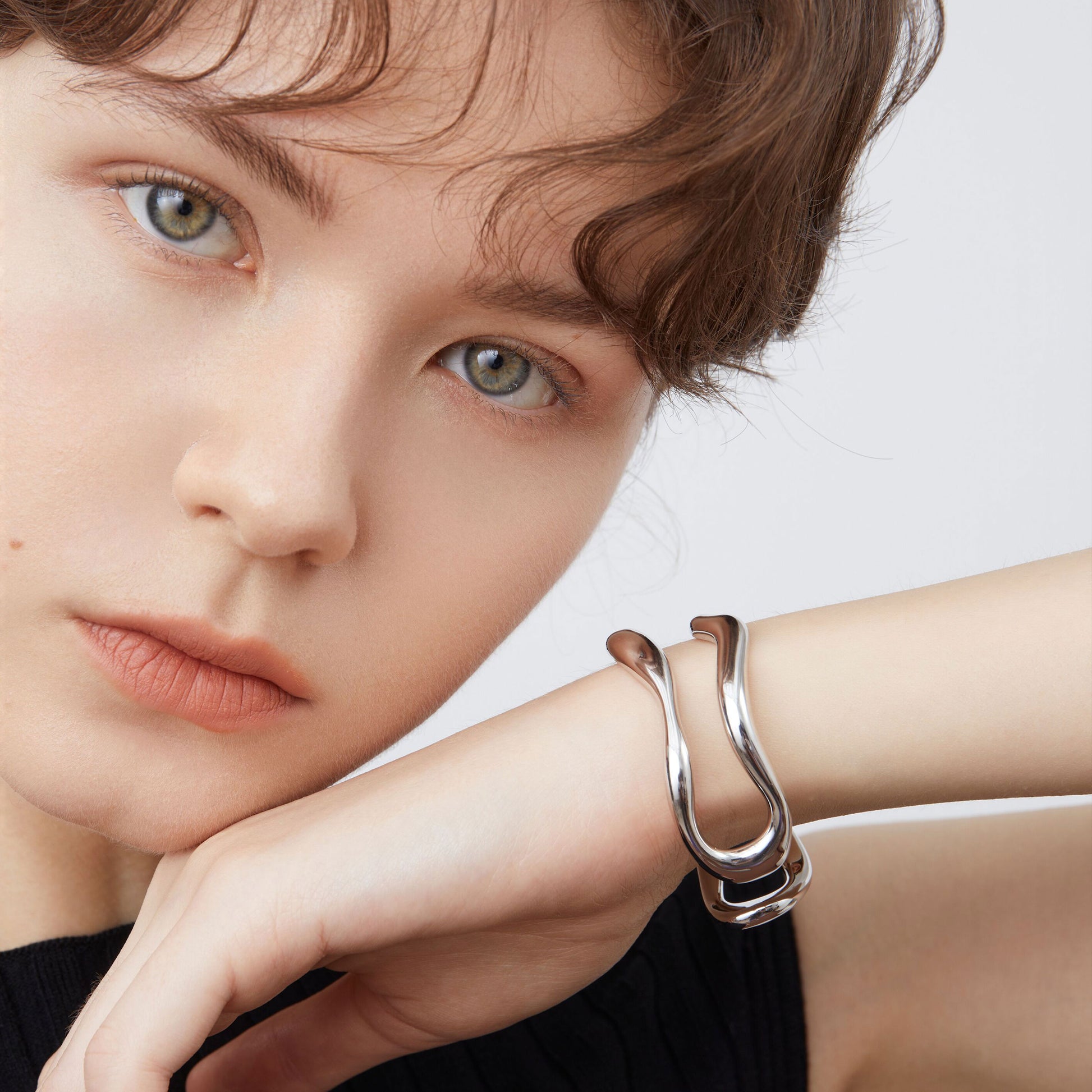 A model wearing the TIKOO liquid metal wave bangle, showcasing its sculptural and modern fit.