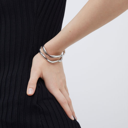 Side view of the silver-tone open cuff bracelet by TIKOO highlighting its sleek wave silhouette.