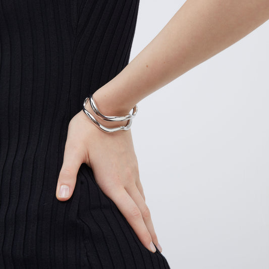 Side view of the silver-tone open cuff bracelet by TIKOO highlighting its sleek wave silhouette.