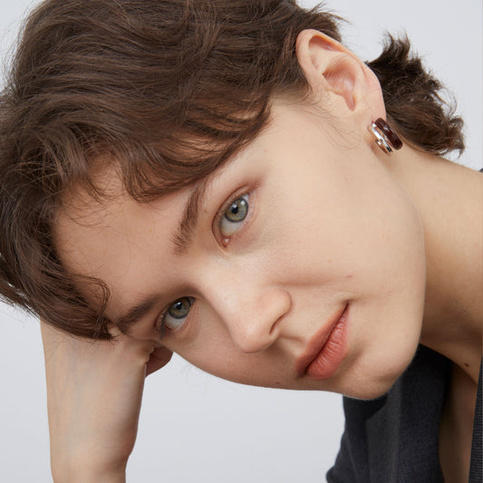 Close-up portrait of a model wearing TIKOO original coffee enamel double-layered earrings.