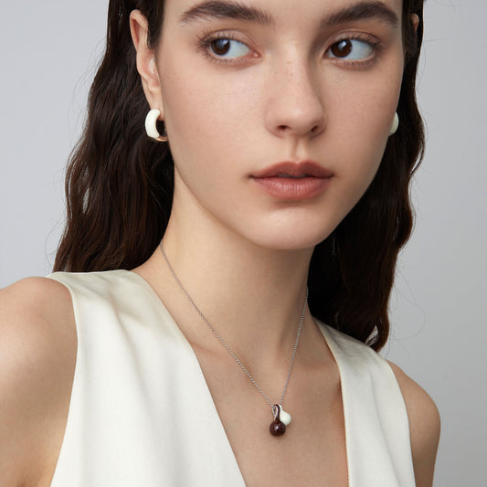 Model wearing TIKOO white enamel sculptural hoops and matching pendant, showcasing a minimalist luxury look.