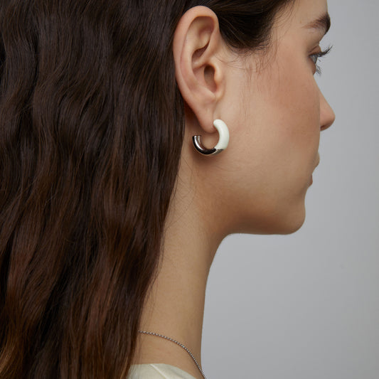 Side view of model wearing chunky white enamel C-hoops, highlighting the bold silhouette and high-shine finish.