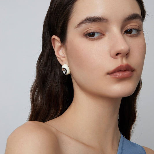 Front view of a fashion model wearing TIKOO minimalist white enamel hoop earrings and a silver capsule necklace, showcasing styling for modern jewelry.