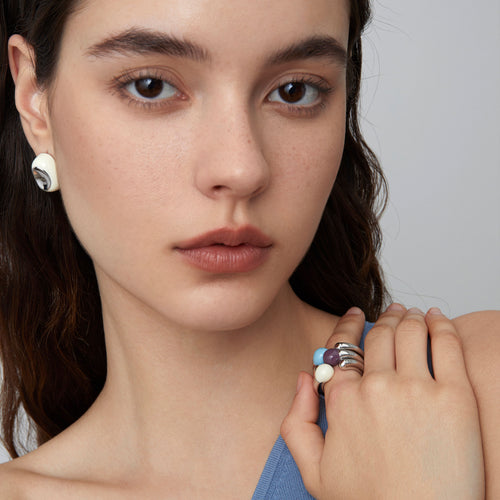 Fashion model wearing a stack of TIKOO sculptural rings in various enamel colors, showcasing a modern jewelry trend.