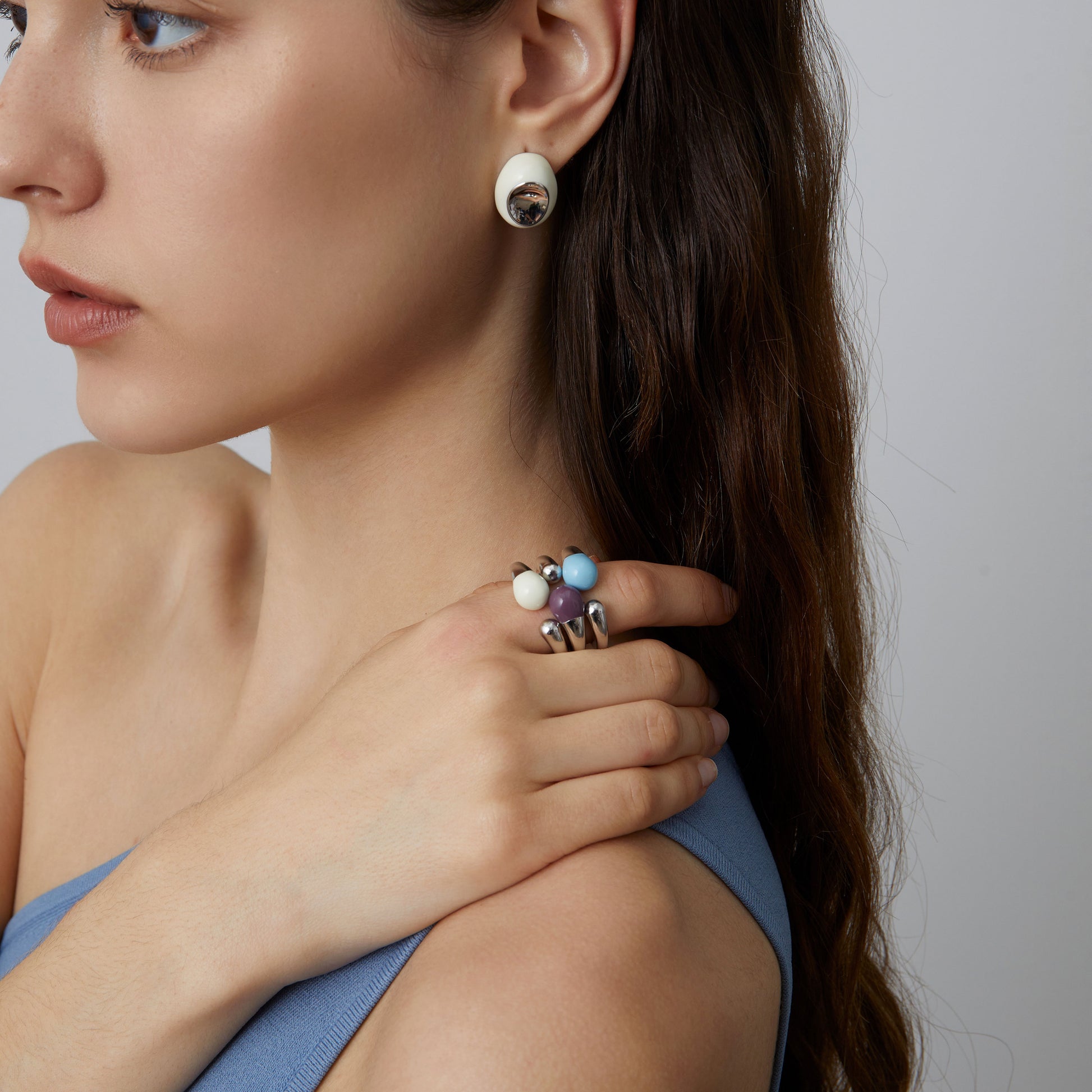 Detailed shot of the TIKOO sculptural open ring in white enamel, showing the fluid metallic design on a hand.