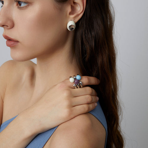 Detailed shot of the TIKOO sculptural open ring in white enamel, showing the fluid metallic design on a hand.