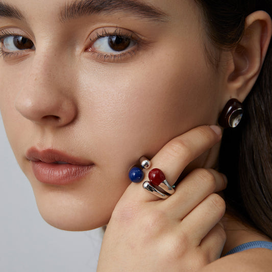 Close-up view of a model wearing the TIKOO blue enamel sculptural ring, highlighting the fluid metal design and glossy finish.