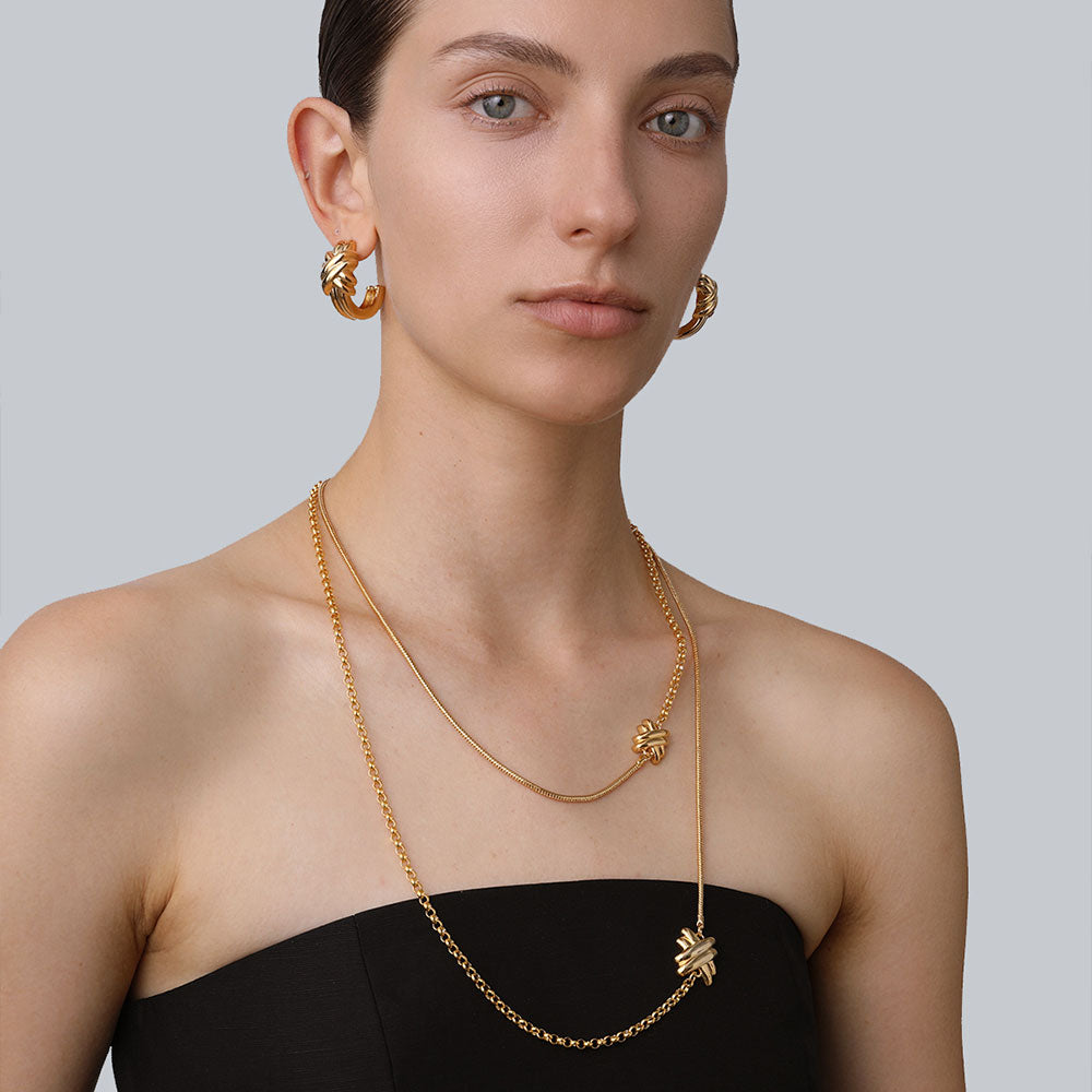 Model showcasing the layered effect of the TIKOO gold knot long necklace paired with matching chunky hoops.