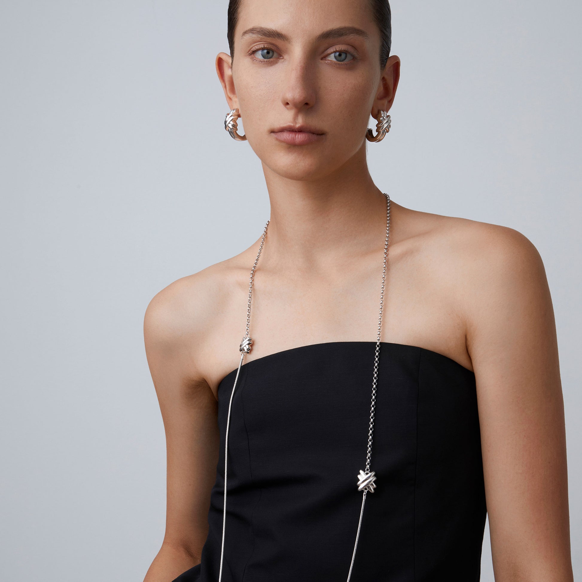 Model showcasing the full length of the TIKOO platinum-plated long knot necklace against a minimalist background.