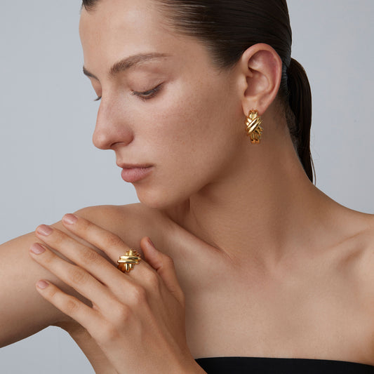Side view of a woman wearing textured 18K gold plated chunky hoops with architectural knot detail.