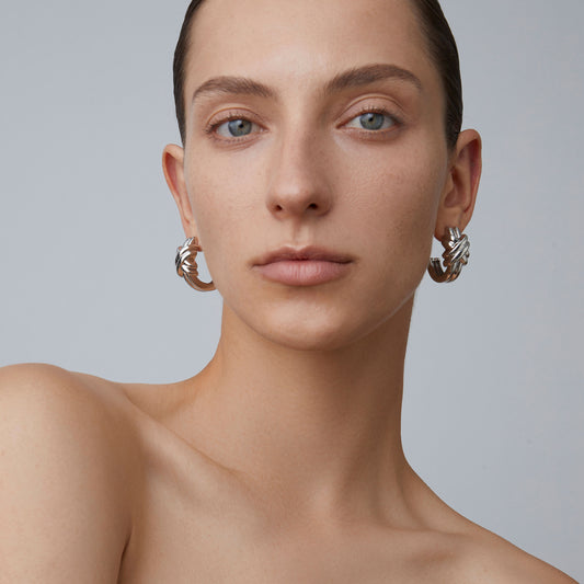 Model styling chunky platinum-plated twisted hoops for a minimalist fashion look.