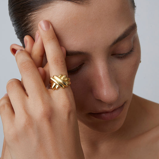 Fashion model showcasing the TIKOO statement gold knot ring against a minimalist background.